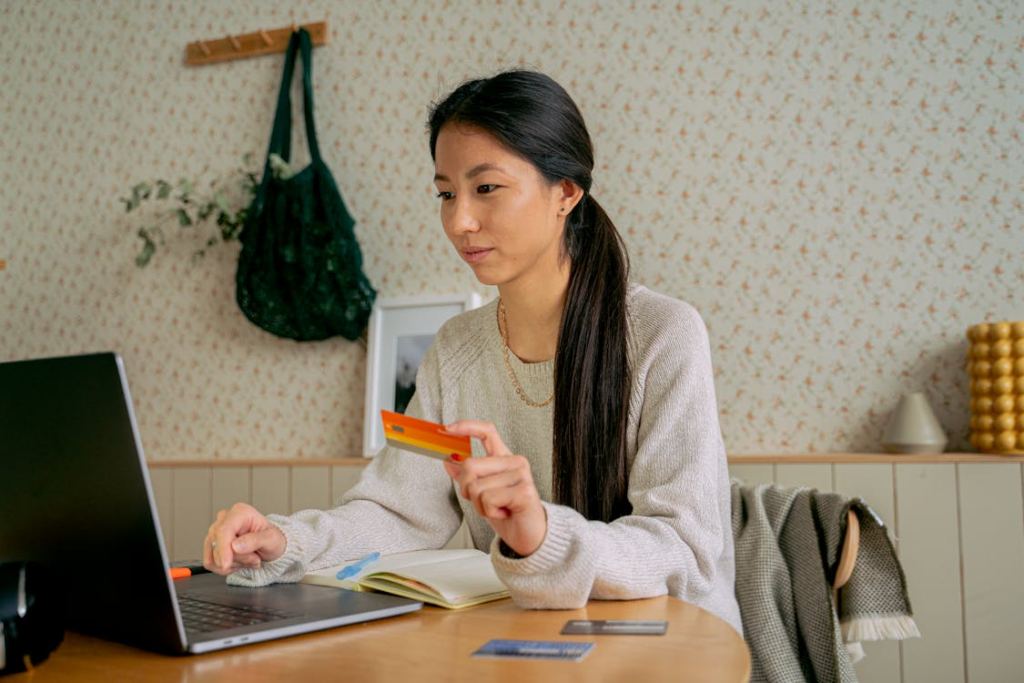 Woman using a laptop and credit card to track streaming spending and review subscription costs.