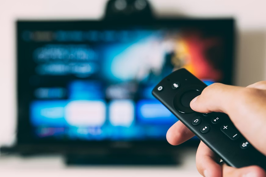 Viewer using a streaming remote illustrating Roku vs Fire TV Stick 4K for everyday viewing.