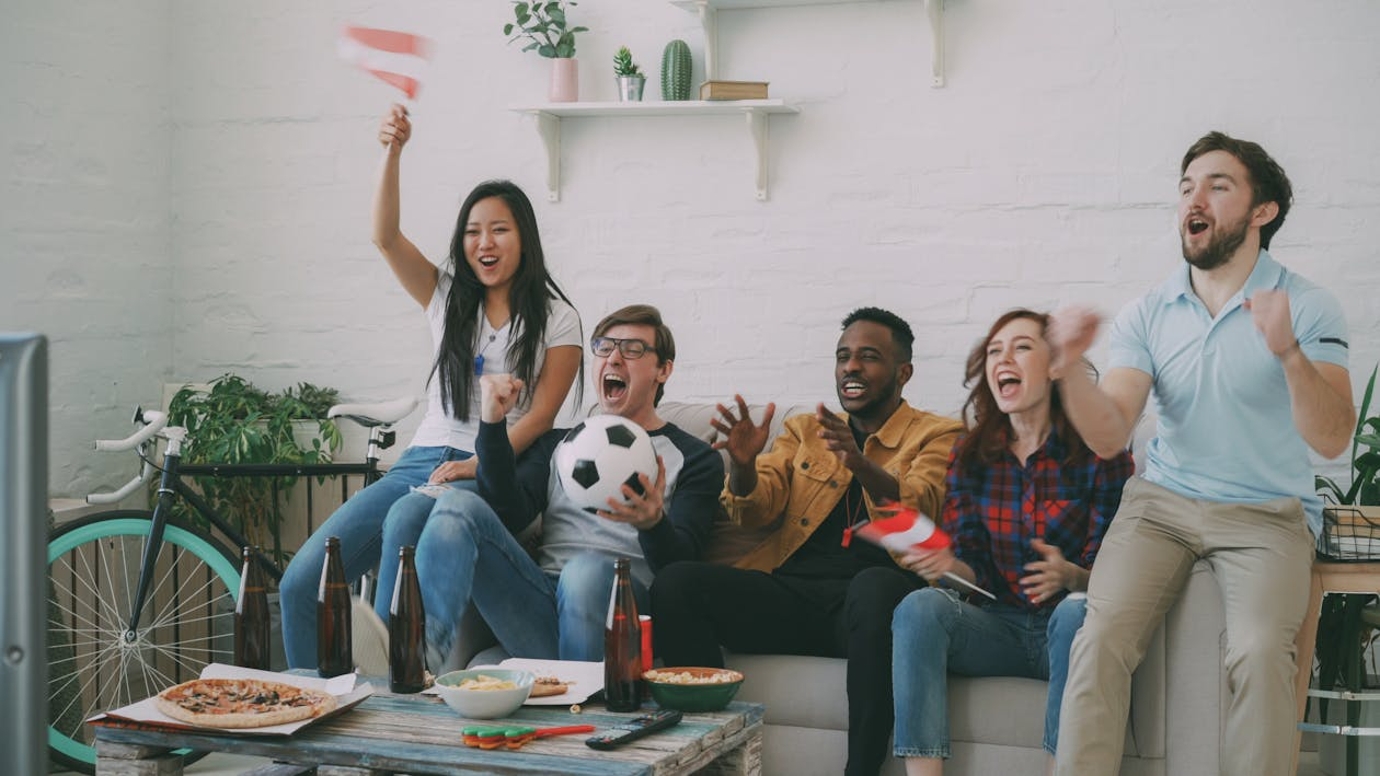 Sports fans watching a live game at home, illustrating Sling TV vs Fubo for streaming coverage.