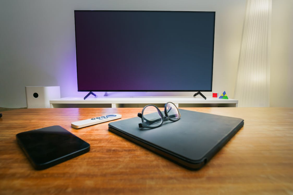 Smart TV vs streaming device setup with a television, remote, tablet, and laptop in a living room.