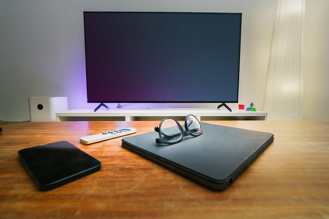 Smart TV vs streaming device setup with a television, remote, tablet, and laptop in a living room.