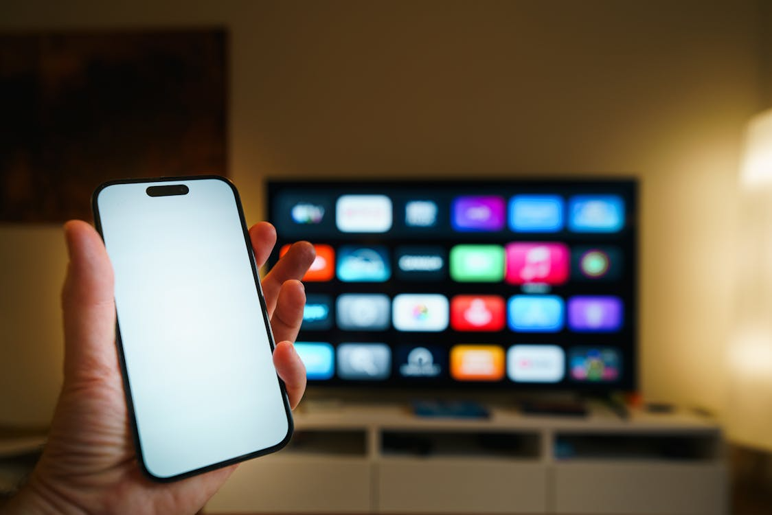 Phone and TV showing streaming apps with viewer deciding which streaming services to keep or cancel.